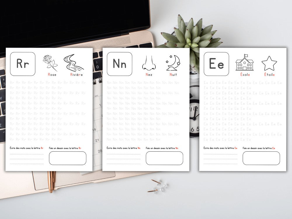 Three flashcards with letters R, N, and E on a desk with a computer and plant.