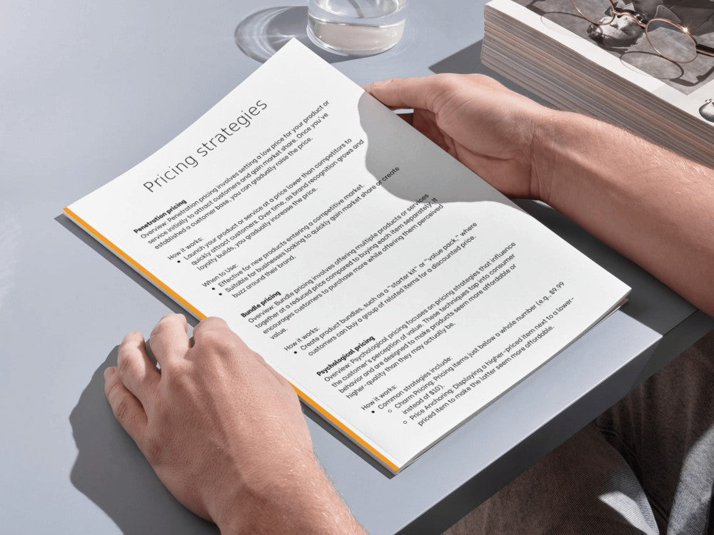 Person holding a book open to a page titled 'Pricing strategies' on a table.