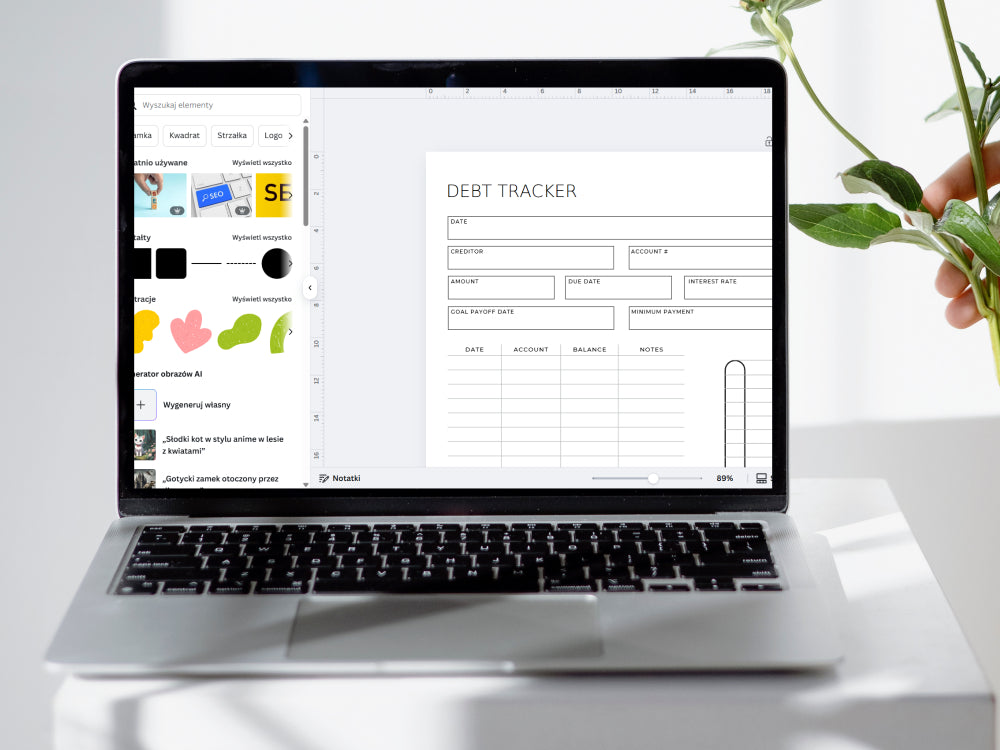 Laptop displaying a debt tracker on a white surface with a plant