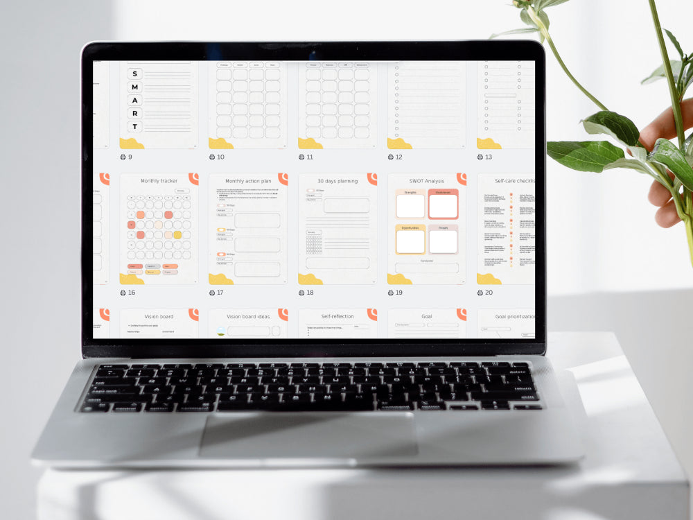 Laptop displaying a user interface design on a white surface with a plant