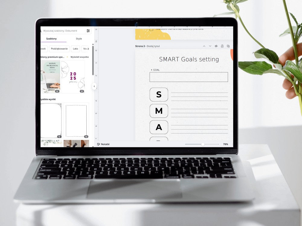 Laptop displaying a SMART Goals setting interface on a white surface with a plant.