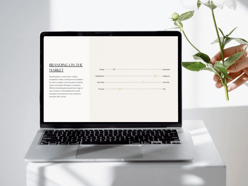 Laptop on a white surface with a hand holding a plant, displaying a branding document.