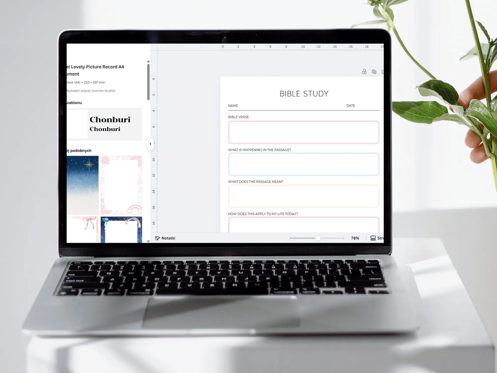 Laptop displaying a Bible study app on a white surface with a plant