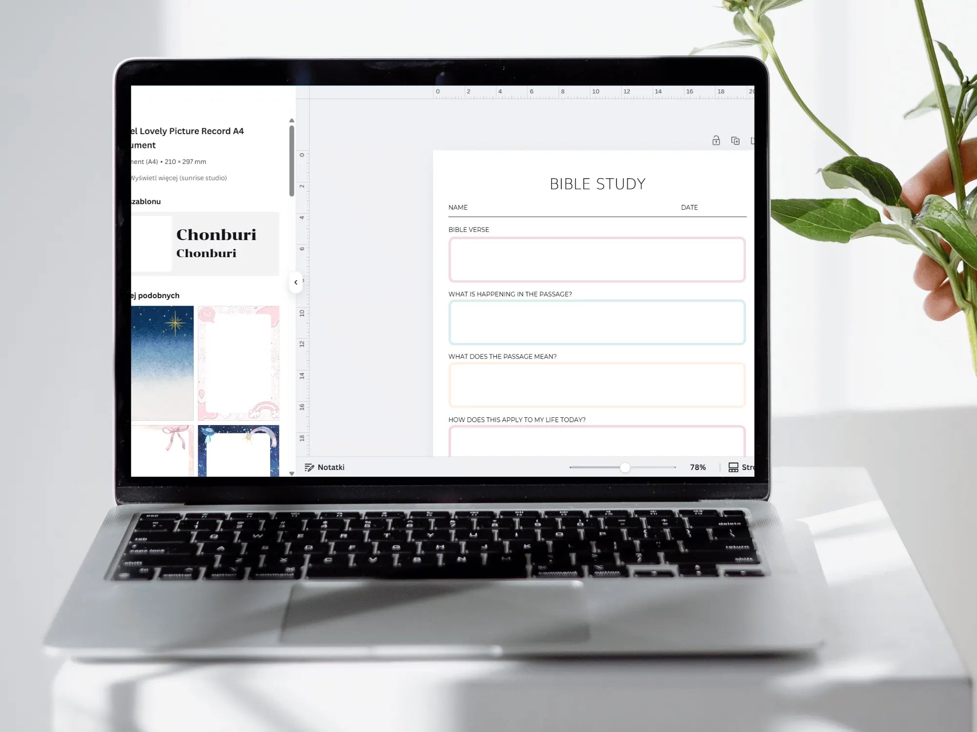 Laptop displaying a Bible study app on a white surface with a plant