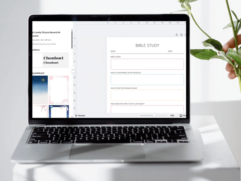 Laptop displaying a Bible study app on a white surface with a plant