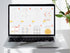 Laptop displaying a digital calendar on a white surface with a plant in the background