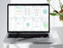 Laptop displaying a digital document on a white surface with a plant in the background