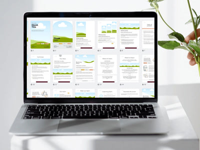 Laptop displaying an eBook on a white surface with a hand holding green leaves.