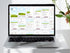 Laptop displaying an eBook on a white surface with a hand holding green leaves.