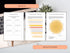 Open book with branded design elements on a desk with a laptop and plant.