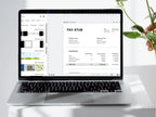 Laptop displaying a pay stub on a white surface with a plant in the background