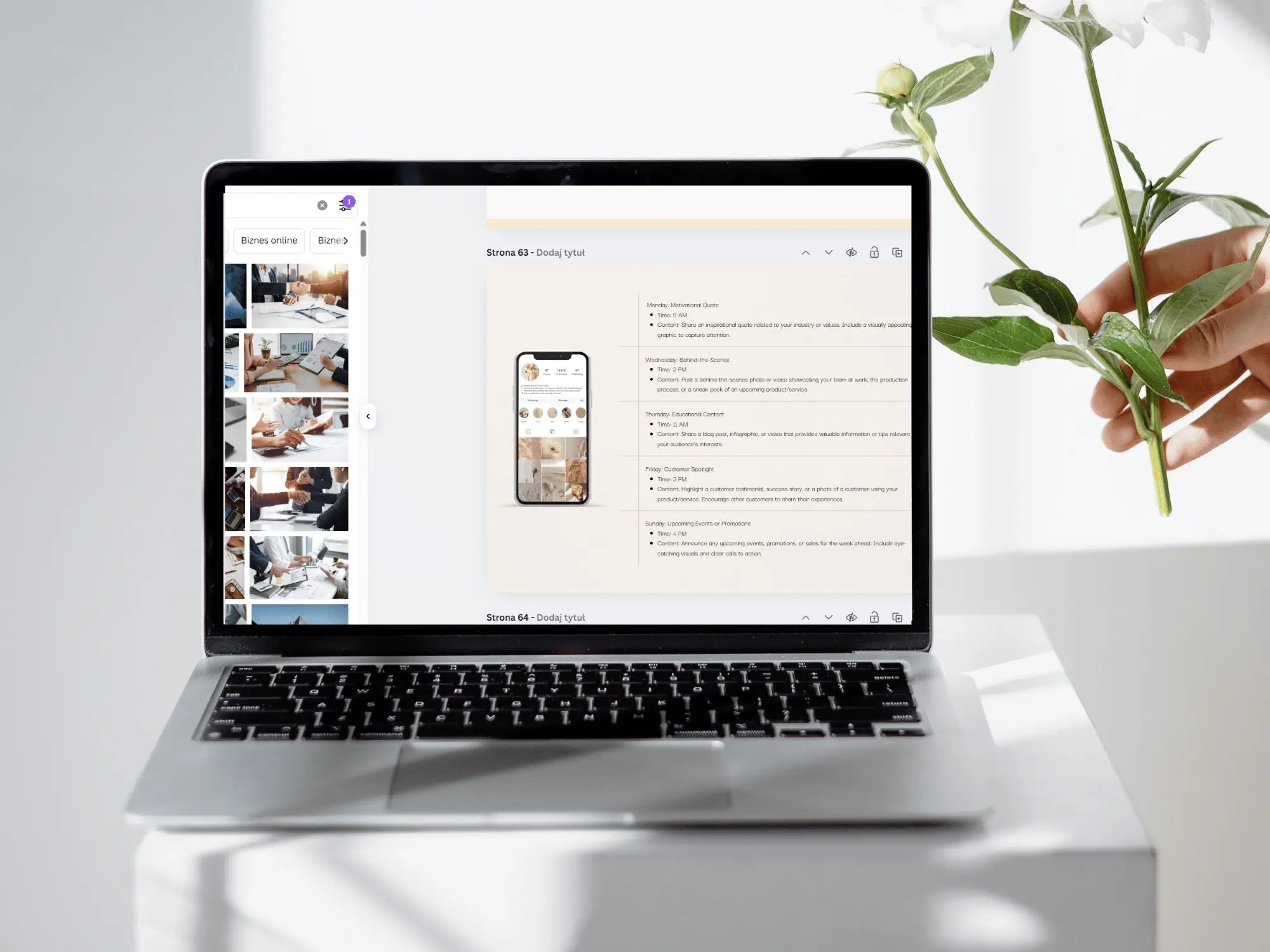 A silver laptop sits on a white pedestal, displaying a website mockup on its screen. A hand holding white flowers is visible on the right side of the frame against a bright, clean white background.