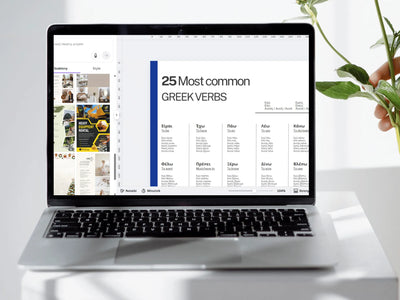 Laptop displaying a webpage with '25 Most common Greek Verbs' on a white surface.