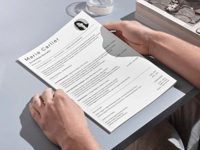 Person holding a resume on a light gray surface