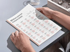 Person holding a book with Russian verb conjugation charts on a light gray surface.