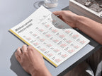 Person holding a book with a French vocabulary chart on a table.