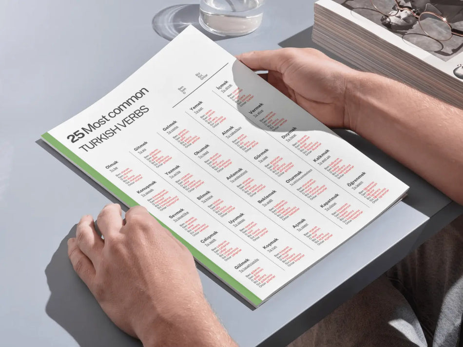 Person holding a book with Turkish verb flashcards on a table