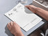 Person holding a notepad with educational content on a light gray surface