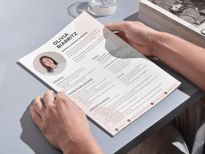 Person holding a resume on a light gray surface