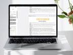 Laptop displaying a December social media planner on a white surface with a plant.