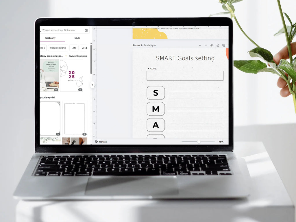 Laptop displaying a SMART Goals setting interface on a white desk with a plant.