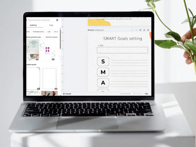 Laptop displaying a SMART Goals setting interface on a white desk with a plant.