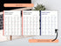 Open book showing pages with English verb lists on a desk with a laptop and plant.