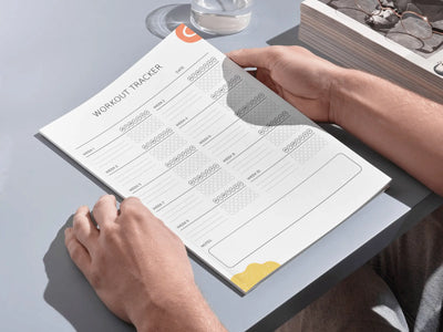 Person holding a planner with a calendar page on a light gray surface