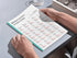 Person holding a Spanish verb chart on a table