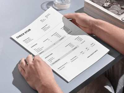Person holding a check stub book on a light gray surface