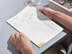 Person using a (debt tracker) on a desk with a glass of water and sunglasses in the background.