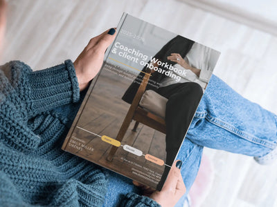 A high-angle, lifestyle shot of a person wearing a blue knit sweater holding a physical printed version of the 