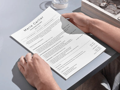 Person holding a resume on a light gray surface