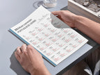 Person holding a tablet displaying a Portuguese verb chart on a light gray surface.